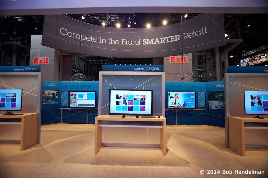 IBM customer technology demo stations with screens on light wood tables