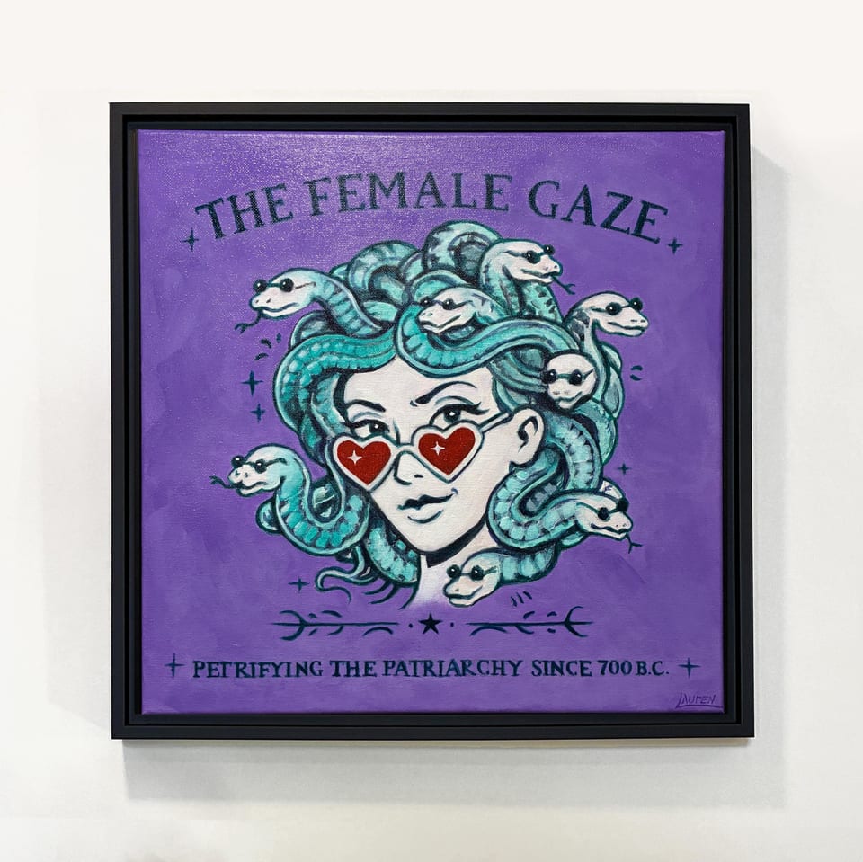 Square framed artwork featuring a stylized Medusa with teal snakes for hair, wearing heart-shaped sunglasses. The background is purple, with the text "THE FEMALE GAZE" and "PETRIFYING THE PATRIARCHY SINCE 700 B.C." in white.